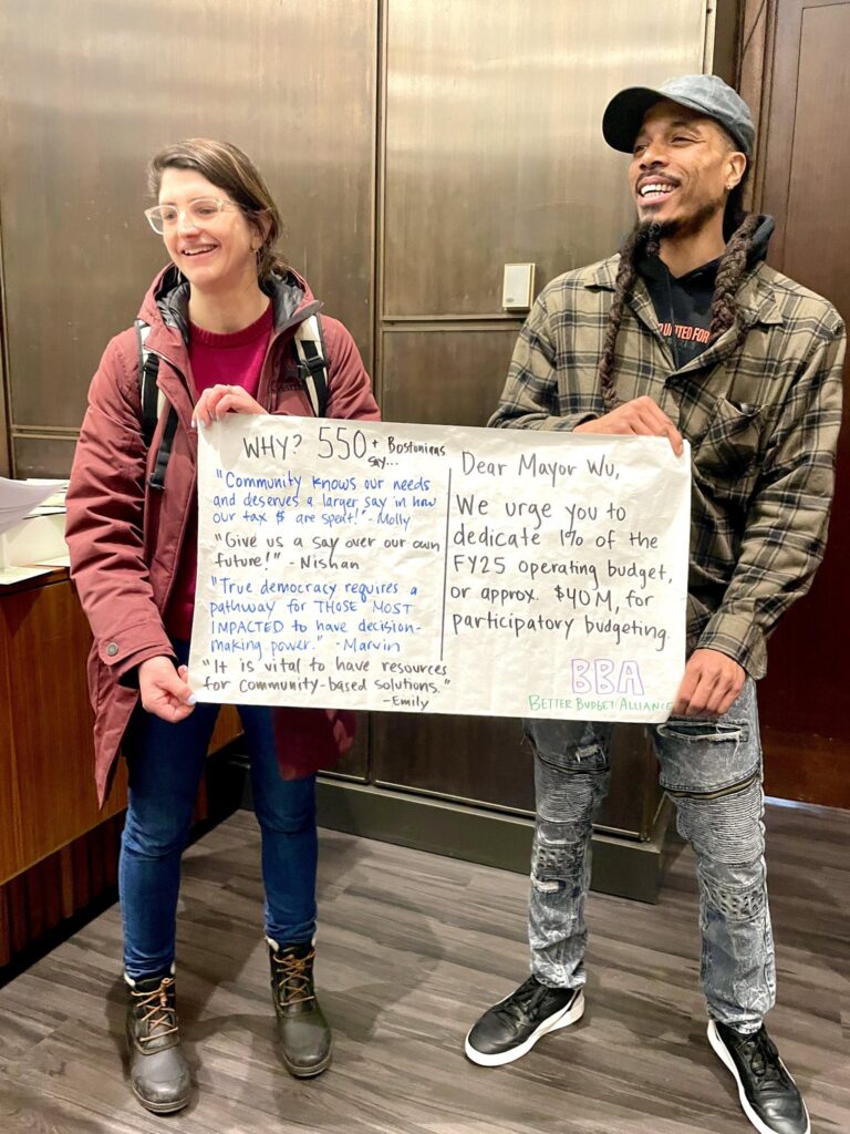 Two BBA activists hold a poster standing indoors