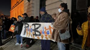 Advocates stand holding a large banner on steps of city hall