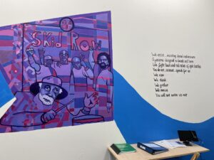 Wall mural with a purple box showing people with fists raised in protest on a white wall with a blue stripe